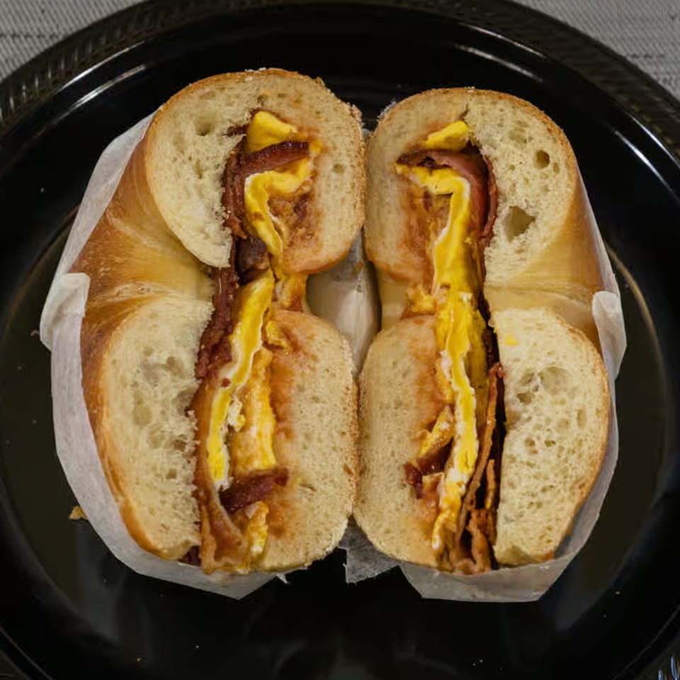 A Bagel Boys bagel, sliced in half, filled with scrambled egg and crispy bacon.