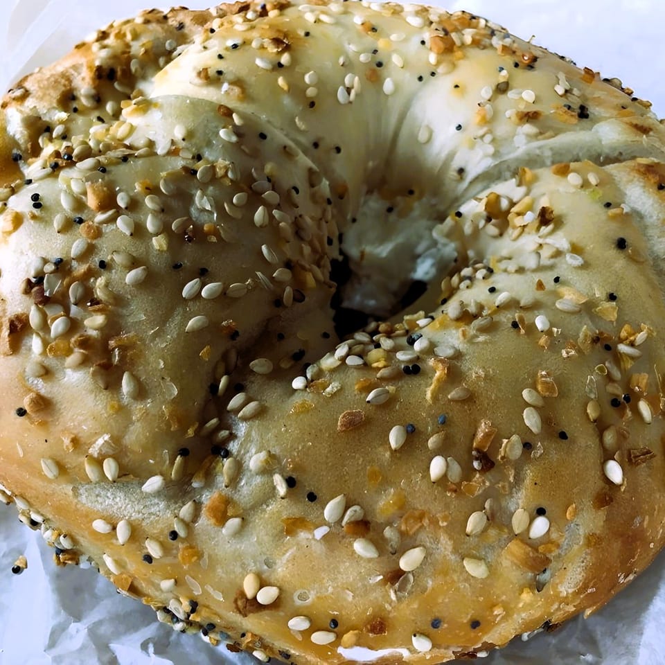 Close-up of a Bagel Boys everything bagel, generously topped with seeds and garlic.